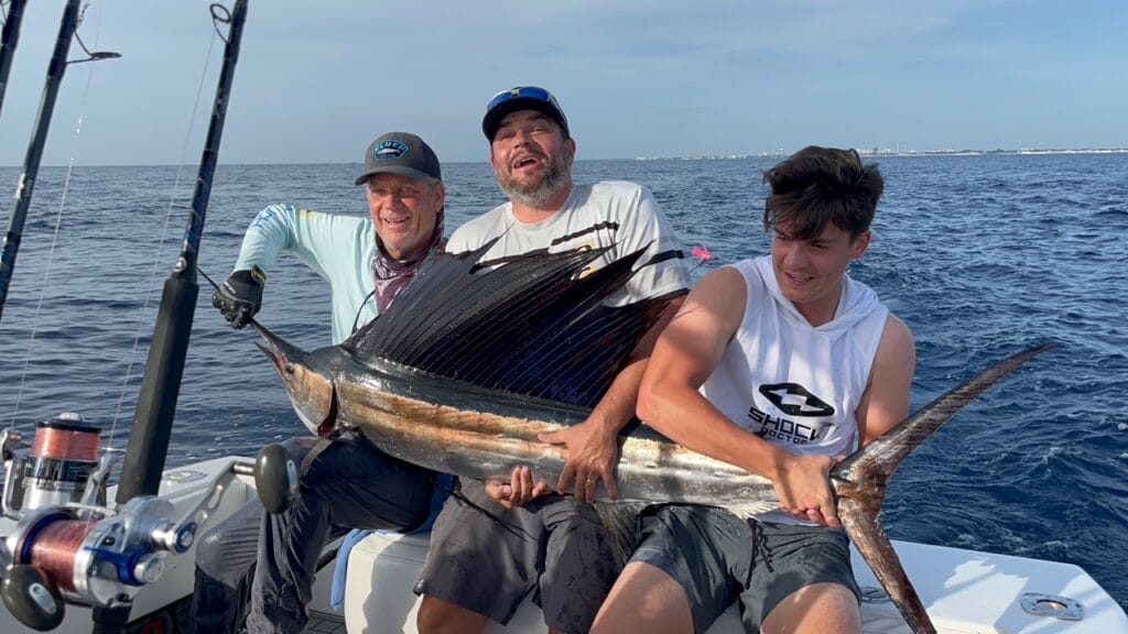 Boat on clear blue ocean with anglers fishing, capturing the essence of private fishing charters West Palm Beach FL.